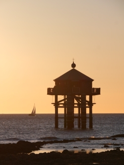 a small tower sitting on top of a beach next to the ocean